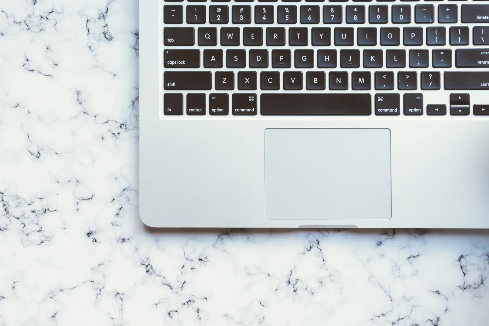 A Mac keyboard and notebook on a clean desk.