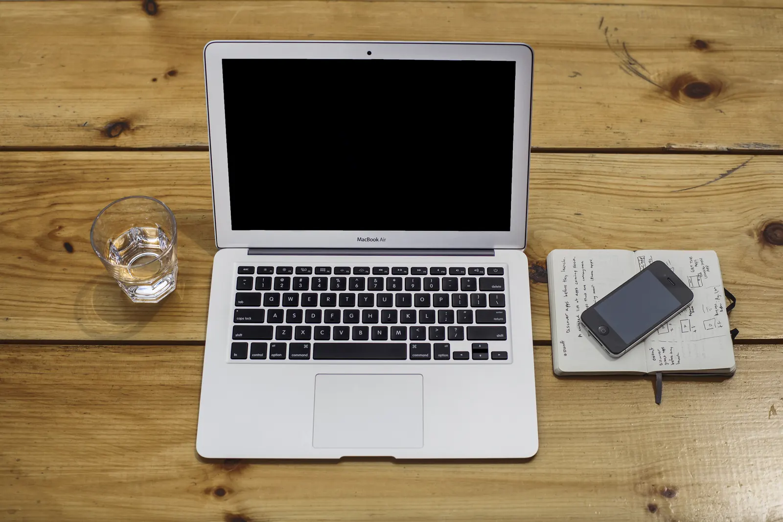 A laptop beside neatly arranged notes and writing tools.