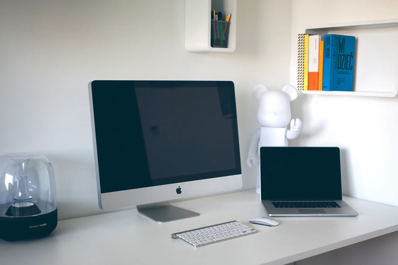 An office table with multiple computers and notebooks.