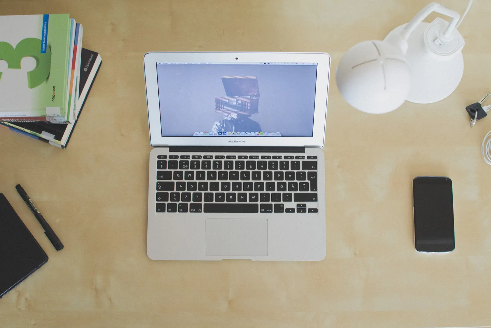 A laptop open on a desk with writing materials nearby.