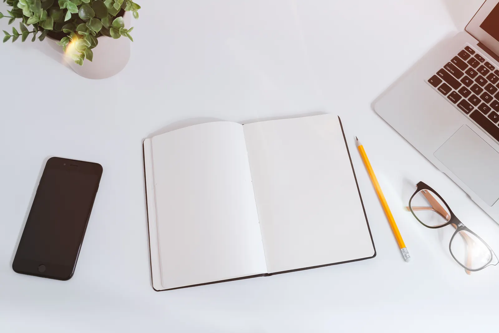 An open notebook and pencil arranged beside a laptop.