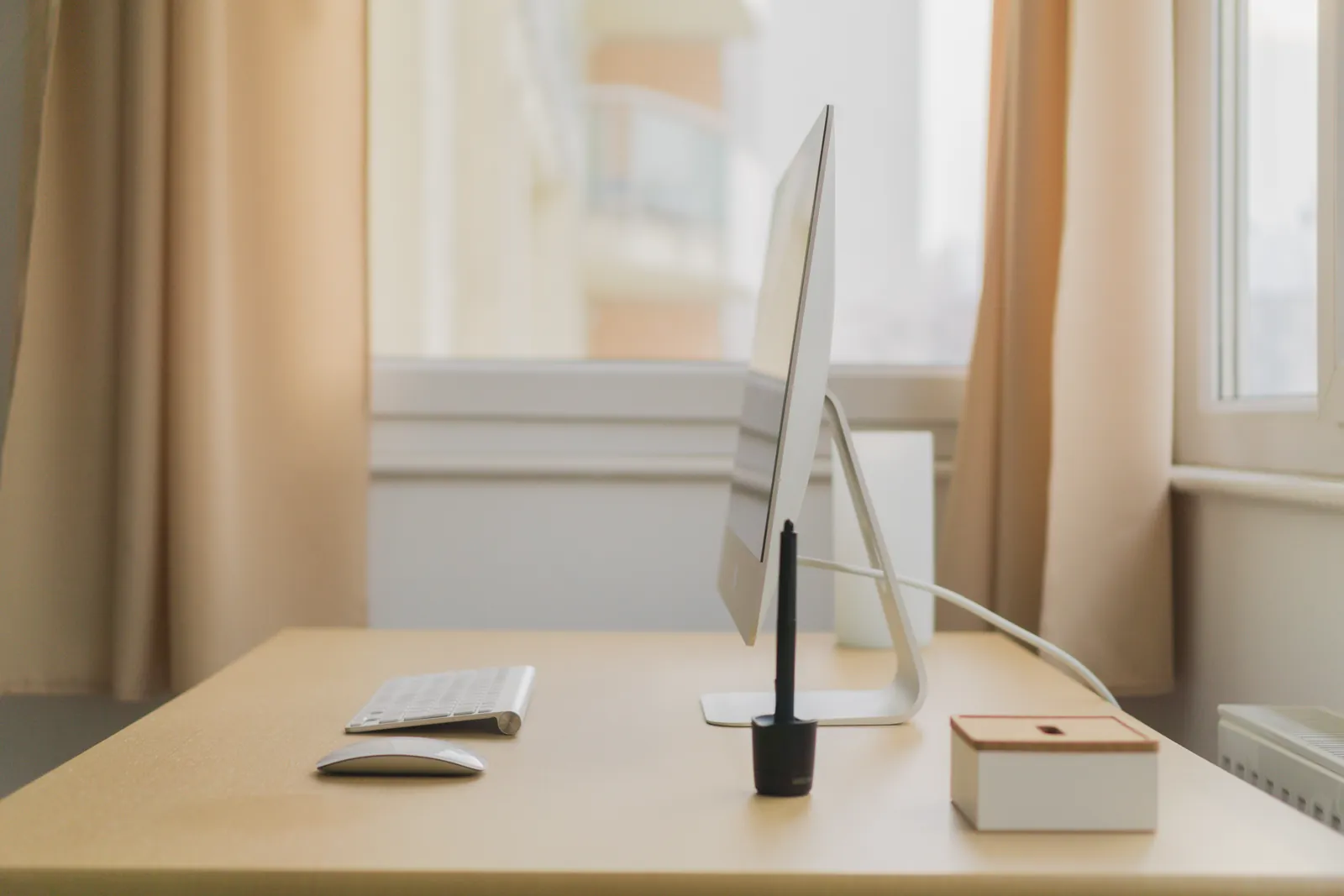 A bright desktop workspace with a laptop, keyboard, and notebook.